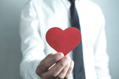 A corporate employee holds a paper heart, representing CSR.